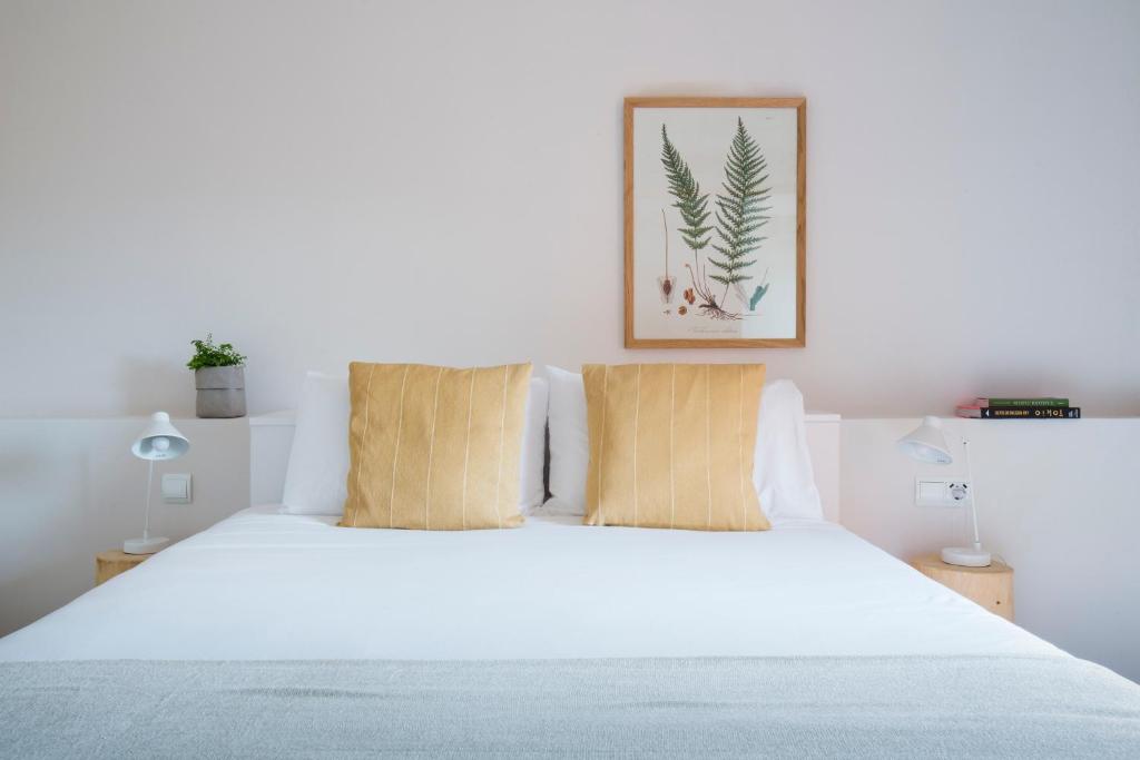 a bedroom with a white bed with two pillows at Hotel Rural Mas de l'Illa in Tivissa