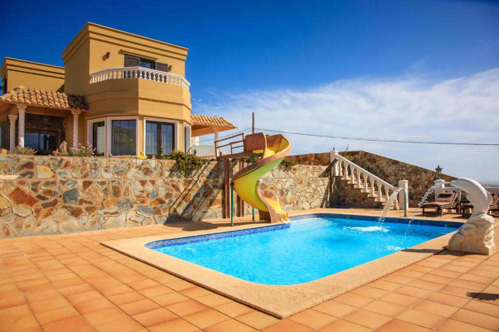 a house with a swimming pool with a slide at VILLA LAS CUEVAS in Tías