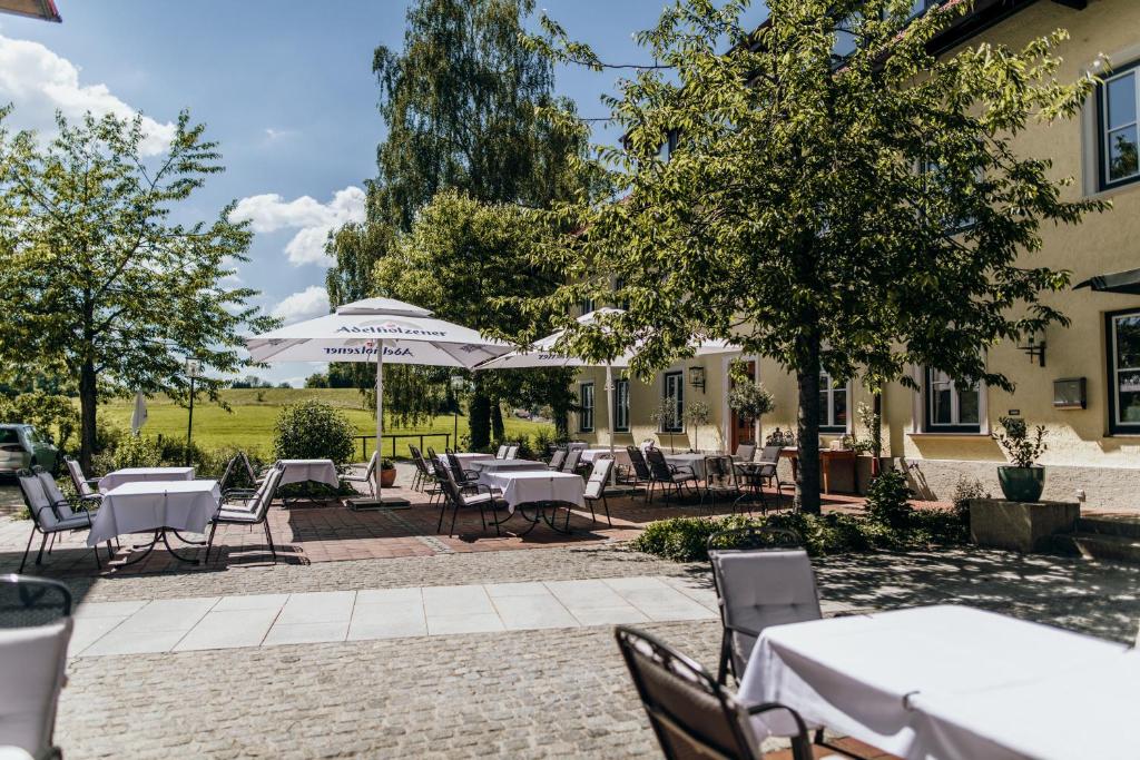 an outdoor patio with tables and chairs and umbrellas at Angermühle Landgasthof in Altenmarkt an der Alz