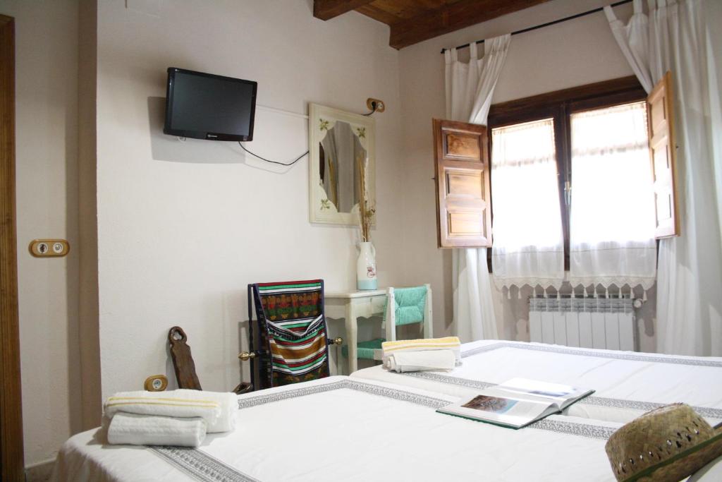 a bedroom with two beds and a tv on the wall at Alojamiento la cañada monfrague in Torrejón el Rubio