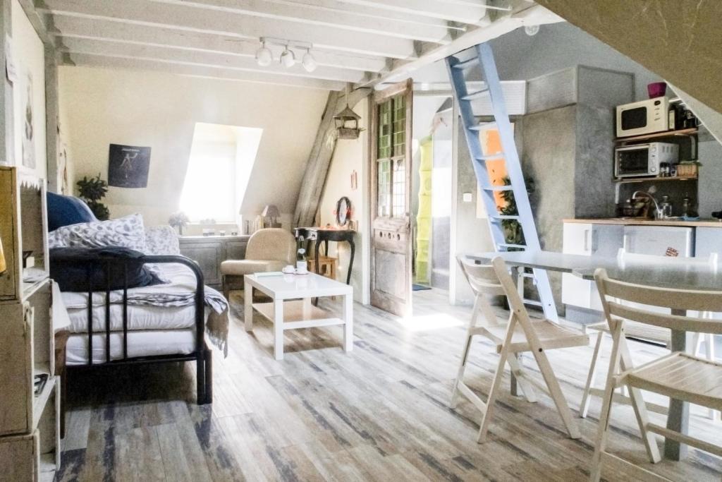 un soggiorno con una scala, un tavolo e delle sedie di Honfleur location a Honfleur