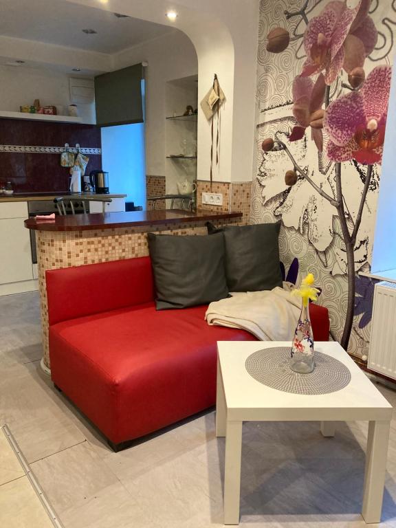 um sofá vermelho numa sala de estar com uma mesa em Apartamenti em Cēsis