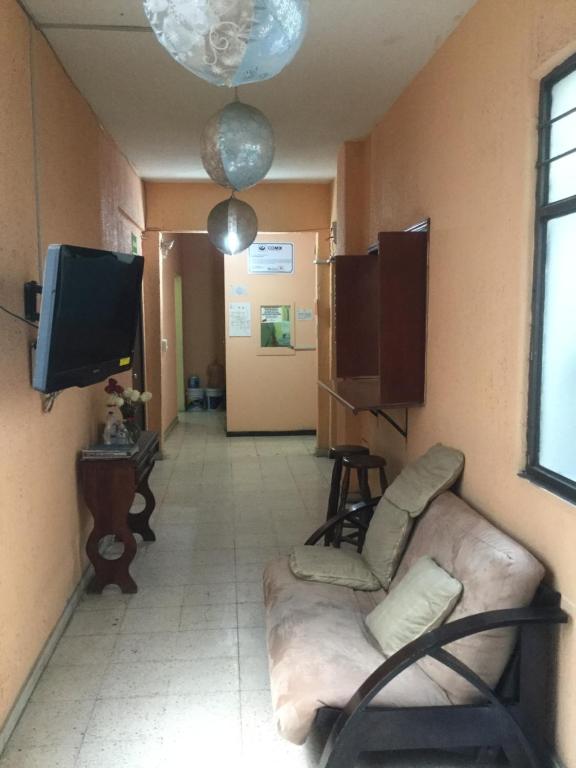 sala de estar con sofá y TV en Pension Zocalo en Ciudad de México