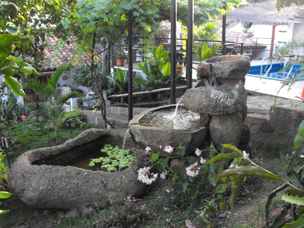 a stone fountain in a garden with flowers at Tinto Hostel in Barichara