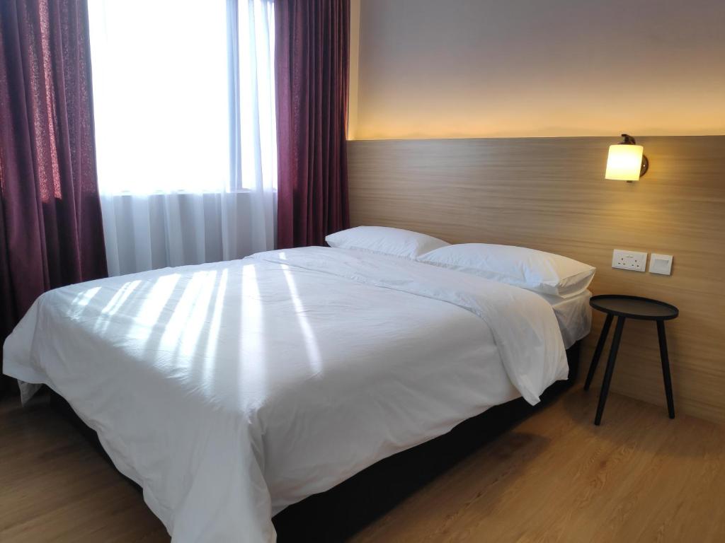 a bedroom with a large white bed with a window at EZ Suites in Bandar Seri Begawan