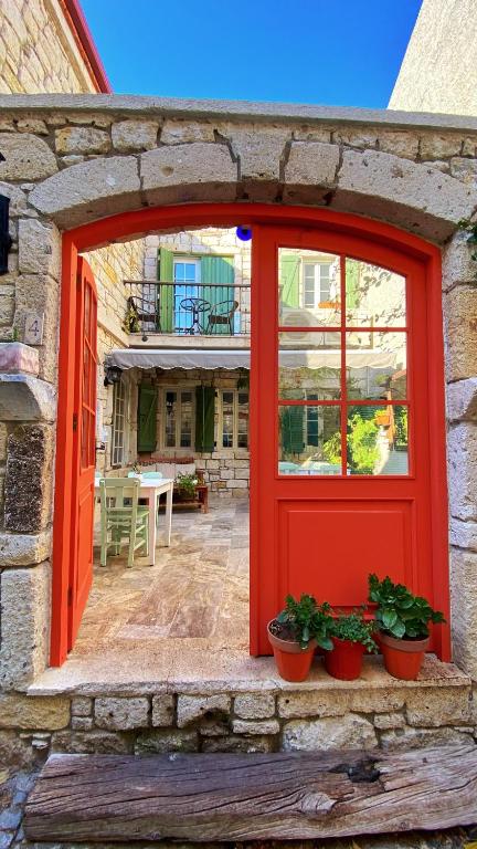 an orange door on a stone building with potted plants at Oberj d'Azur Alaçatı in Alaçatı