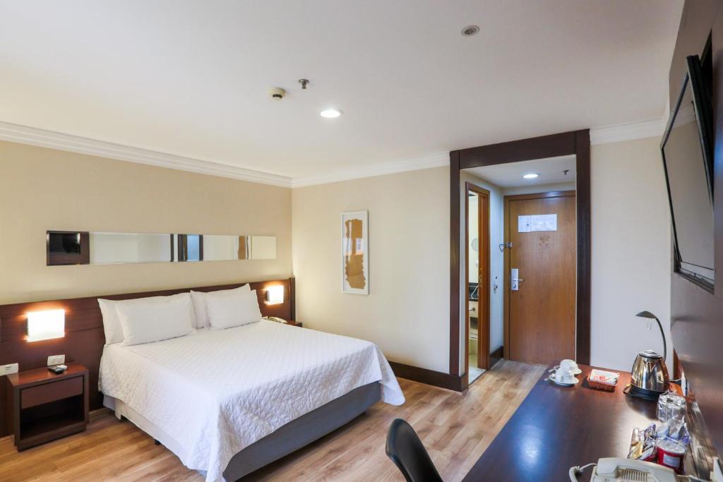 聖保羅的住宿－泛美孔戈尼亞斯行政酒店，一间卧室配有一张床和一张桌子及椅子
