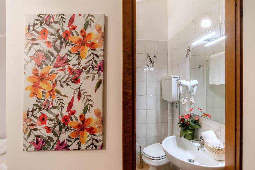 a bathroom with a toilet and a flower painting on the wall at Plaza Rooms Ciampino in Ciampino