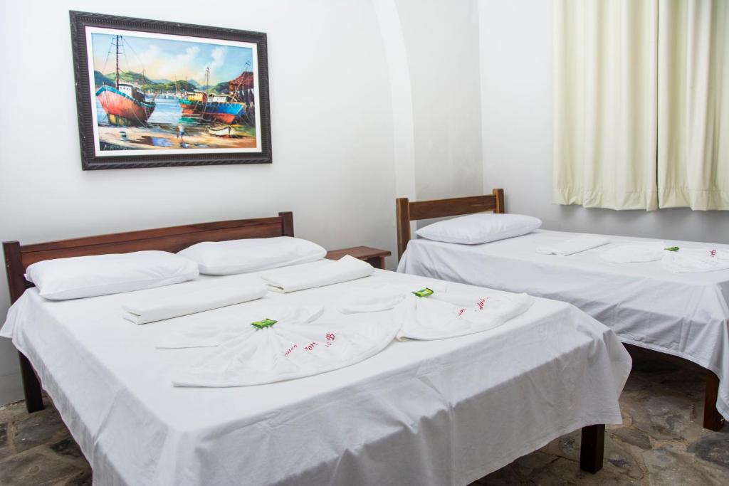 2 camas en una habitación con sábanas blancas en Pousada Porto das Barcas en Parnaíba
