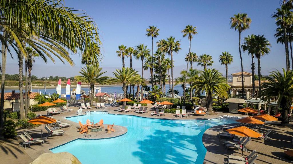 une grande piscine avec des chaises, des parasols et des palmiers dans l'établissement San Diego Mission Bay Resort, à San Diego