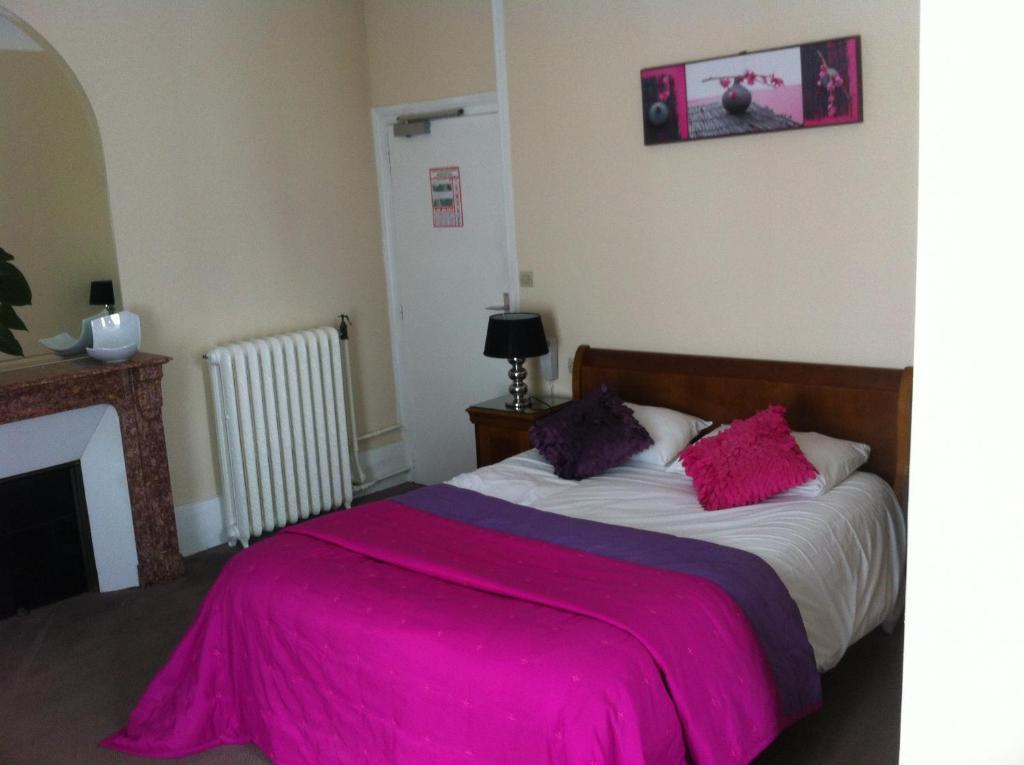 una camera con un letto e una coperta rosa di Hotel La Poularde a Gien