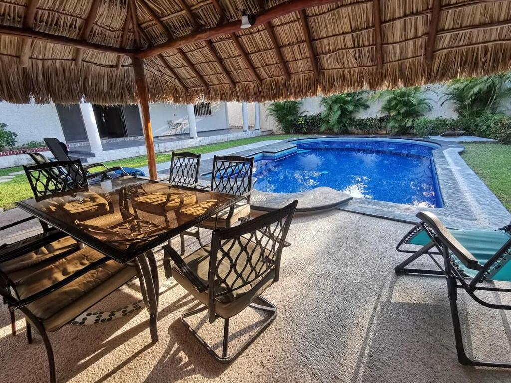 a patio with a table and chairs and a pool at La Quinta de Don Hugo in Ixtapa