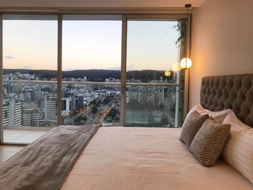een slaapkamer met een groot bed en een groot raam bij Suite Apartamento Espectacular Vista La Carolina - ONE Quito in Quito