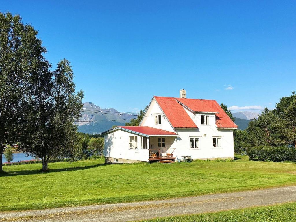 een wit huis met een rood dak op een groen veld bij 6 person holiday home in Storsteinnes in Storsteinnes