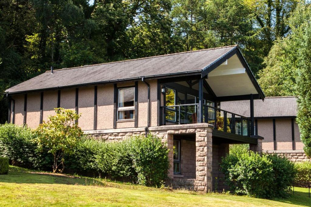 una casa con una gran ventana en el lateral en CELEBRATE AT THE WORLD FAMOUS LOCH LOMOND RESORT CAMERON HOUSE - Sleeps 6, en Alexandria