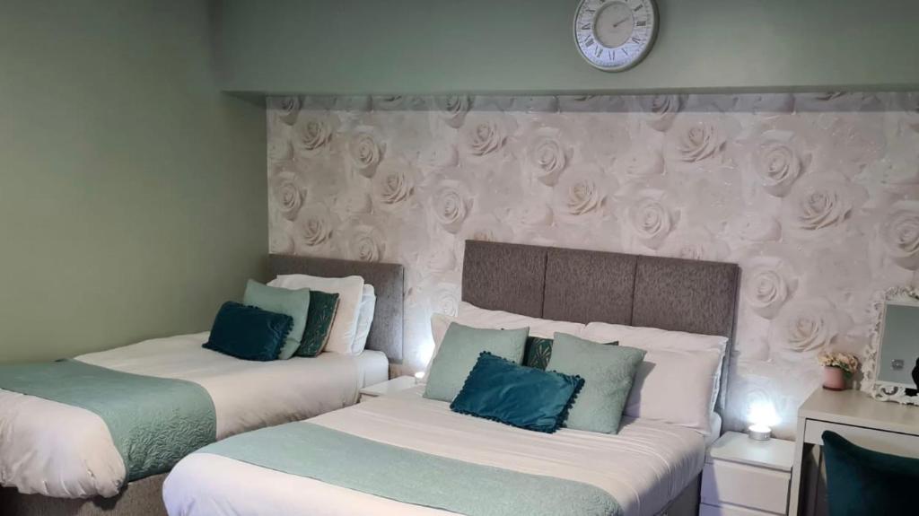 a bedroom with two beds and a clock on the wall at The Rose Garden Room - self contained studio in Ballycastle