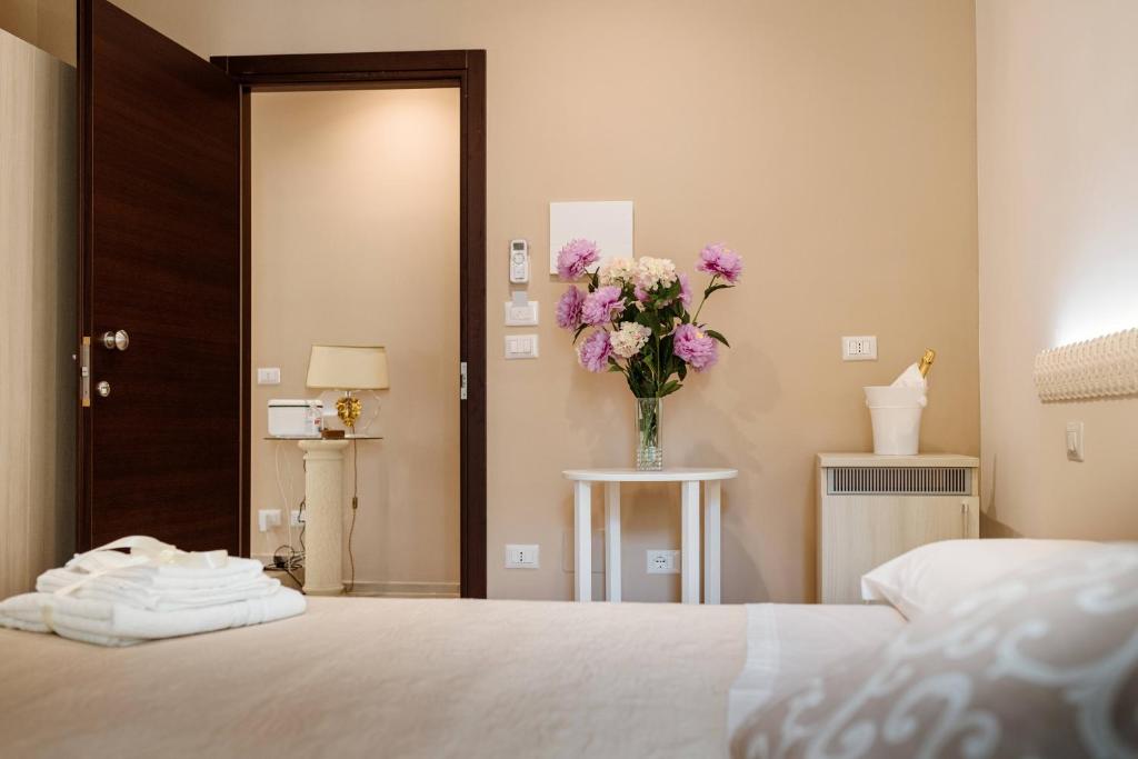 1 dormitorio con 1 cama y un jarrón de flores en BaroccoSuite, en Lecce