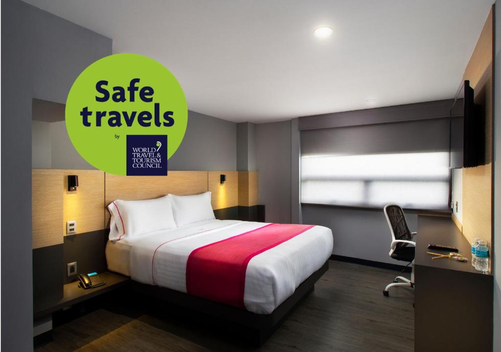 メキシコシティにあるHotel MX aeropuertoのベッドと安全な旅行を読むサイン付きのホテルルーム