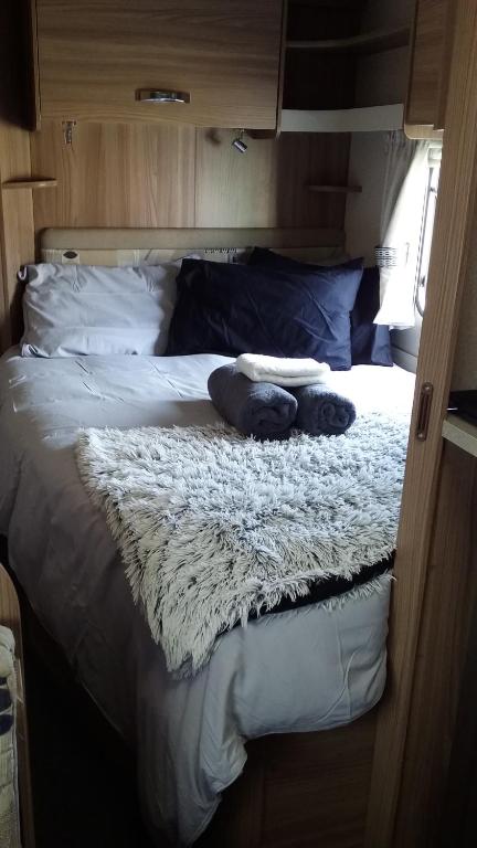Una cama en una caravana con dos almohadas. en Caravan Glamping Accommodation en Te Awamutu