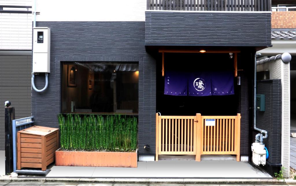 eine Haustür eines schwarzen Hauses mit einem Zaun in der Unterkunft Hotel Traveling Bridge Nijojo in Kyoto