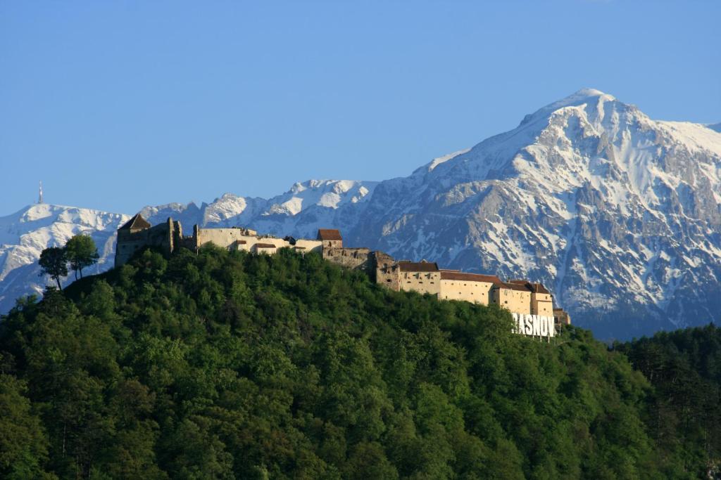 a castle on a hill with mountains in the background at Rem's Pension in Râşnov