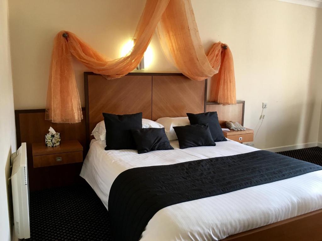 カロンプトンにあるPadbrook Park Hotelのベッドルーム1室(オレンジ色のカーテンが付いた大型ベッド1台付)