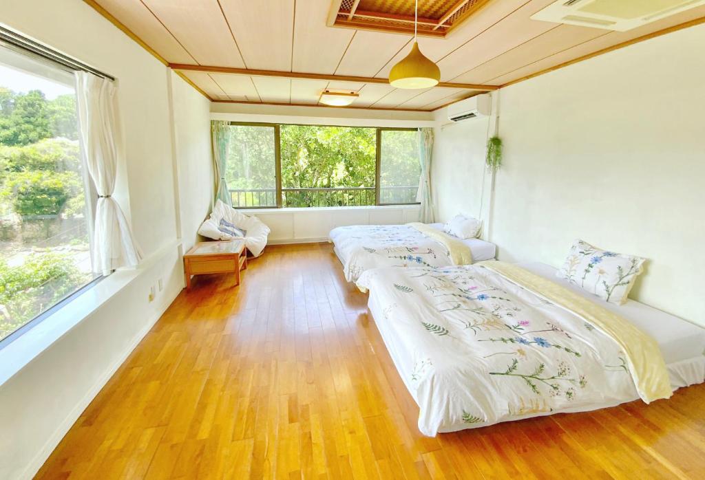 two beds in a room with a large window at イリワ -stay&coffee iriwa- in Ishigaki Island