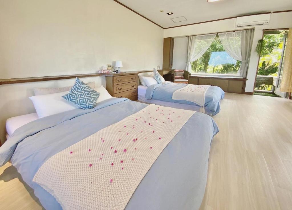 a bedroom with two beds and a window at イリワ -stay&coffee iriwa- in Ishigaki Island