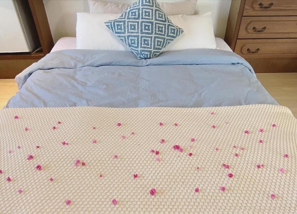 a bed with pink flower petals on it at イリワ -stay&coffee iriwa- in Ishigaki Island