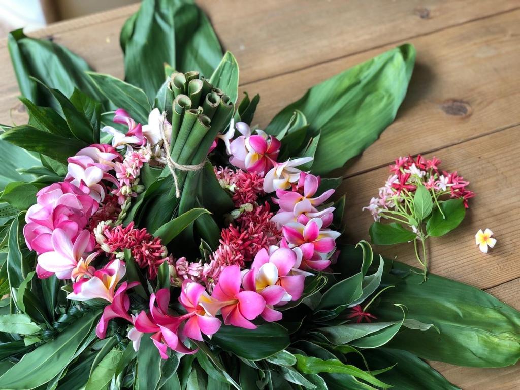 a bouquet of flowers on a wooden table at イリワ -stay&coffee iriwa- in Ishigaki Island