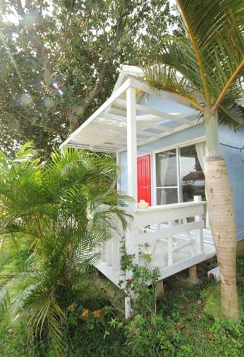 a white house with a red door and a palm tree at イリワ -stay&coffee iriwa- in Ishigaki Island