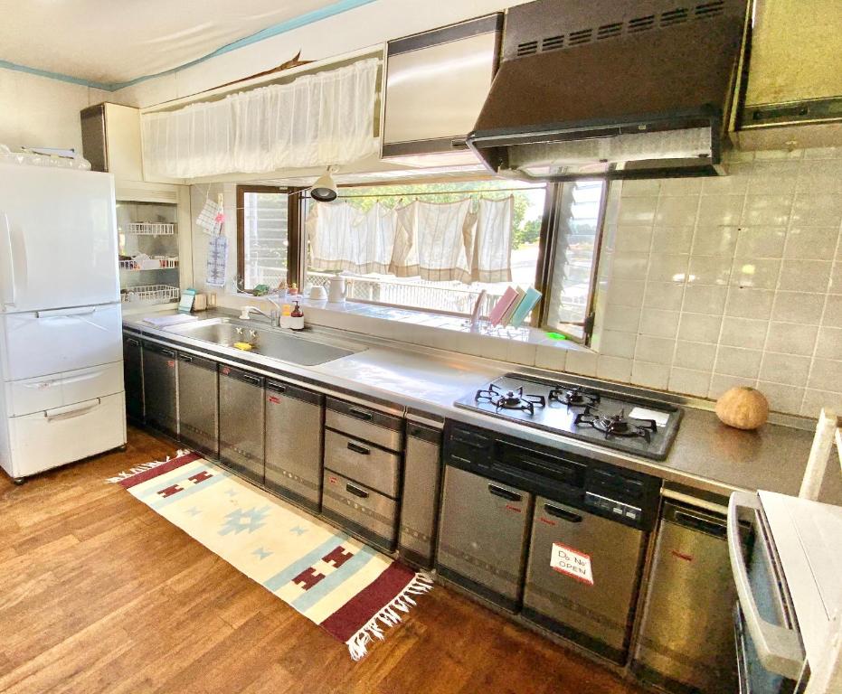 a kitchen with stainless steel appliances and a white refrigerator at イリワ -stay&coffee iriwa- in Ishigaki Island