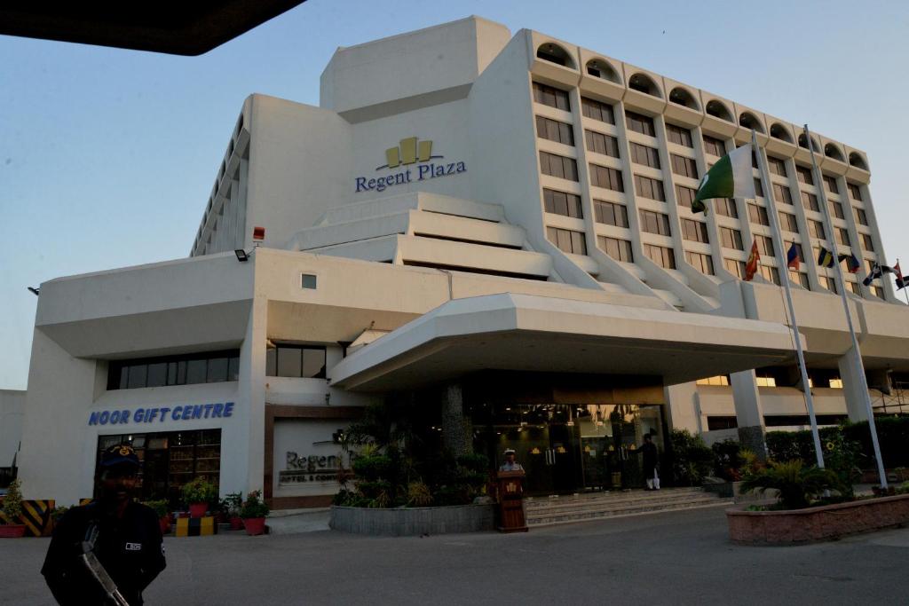 a hotel building with a man walking in front of it at Regent Plaza Hotel & Convention Center in Karachi