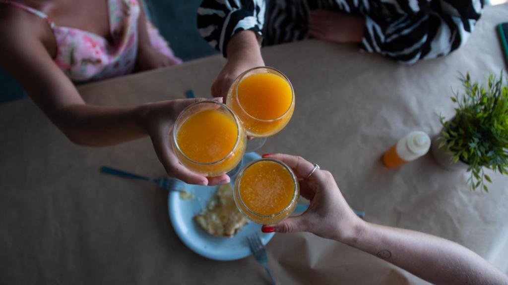 two people holding up two glasses of orange juice at Livikon by the Sea in Hora Sfakion