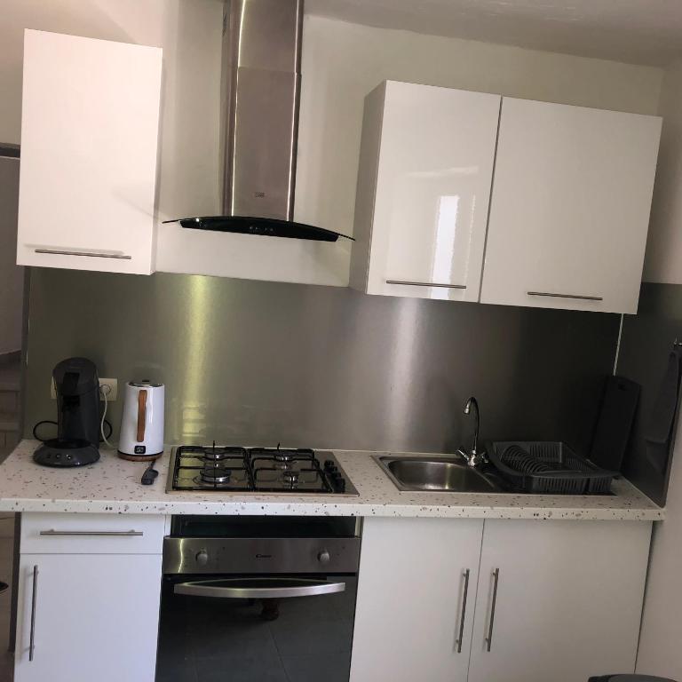 La cuisine est équipée de placards blancs, d'une cuisinière et d'un évier. dans l'établissement Gîte Luna, à Sablet