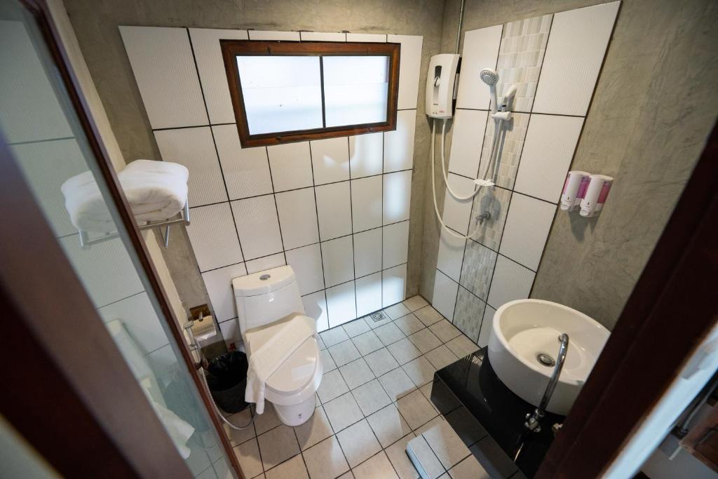 Compact tiled bathroom with a walk-in shower, toilet, and pedestal sink.