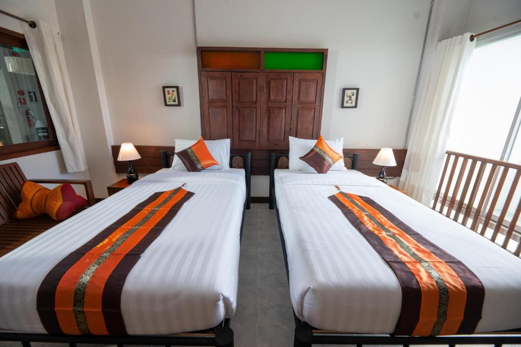 A twin room with two single beds, a small sofa and a bright window-side railing.