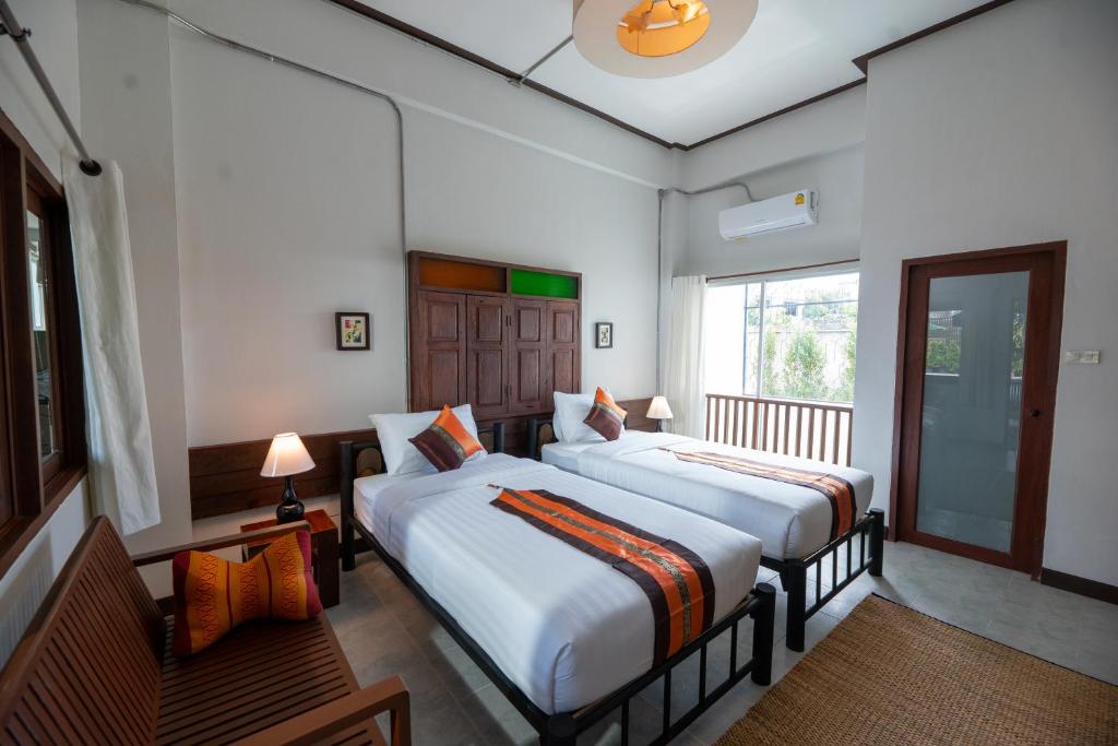A wider view of a twin room with air conditioning, seating and a window.