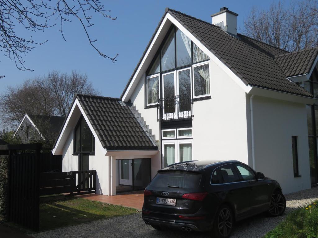 a black car parked in front of a white house at Ruime comfortabele villa Ouddorp in Ouddorp