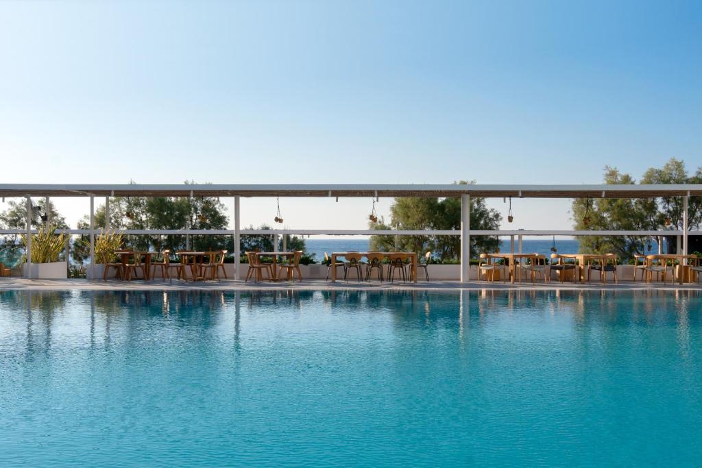 a swimming pool with chairs and blue water at Kamari Beach Hotel in Kamari