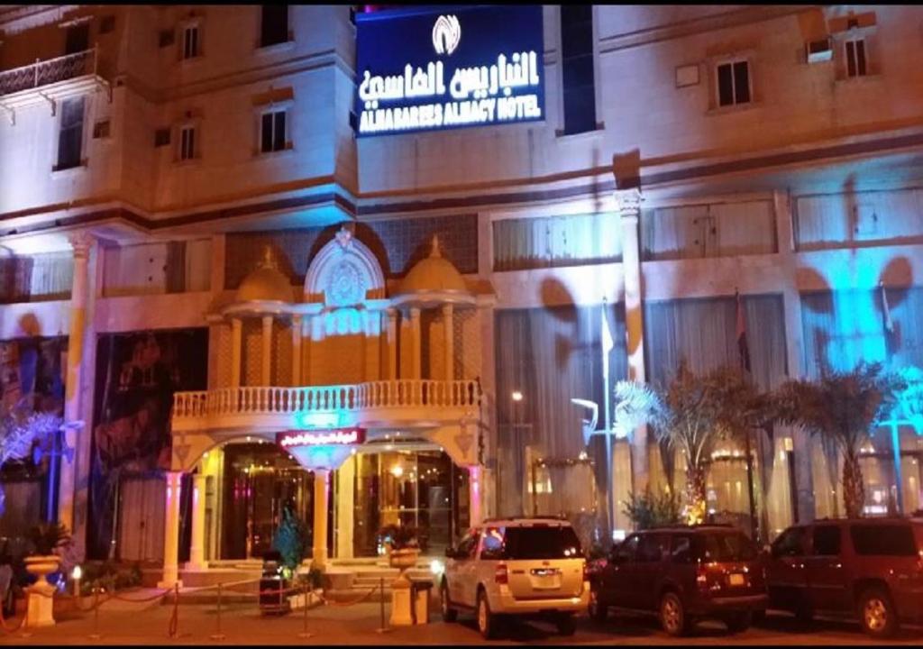 un edificio con coches aparcados delante de él por la noche en Al Nabarees Al Masi Hotel, en Yeda