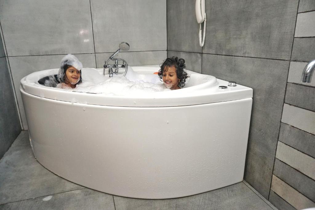 two children are sitting in a bath tub at La Niebla Farm Resort in Ooty