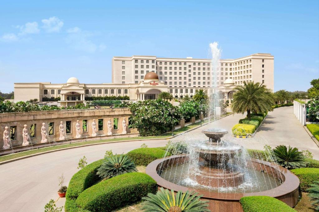 a fountain in a park in front of a building at Ramada by Wyndham Lucknow Hotel and Convention Center in Lucknow