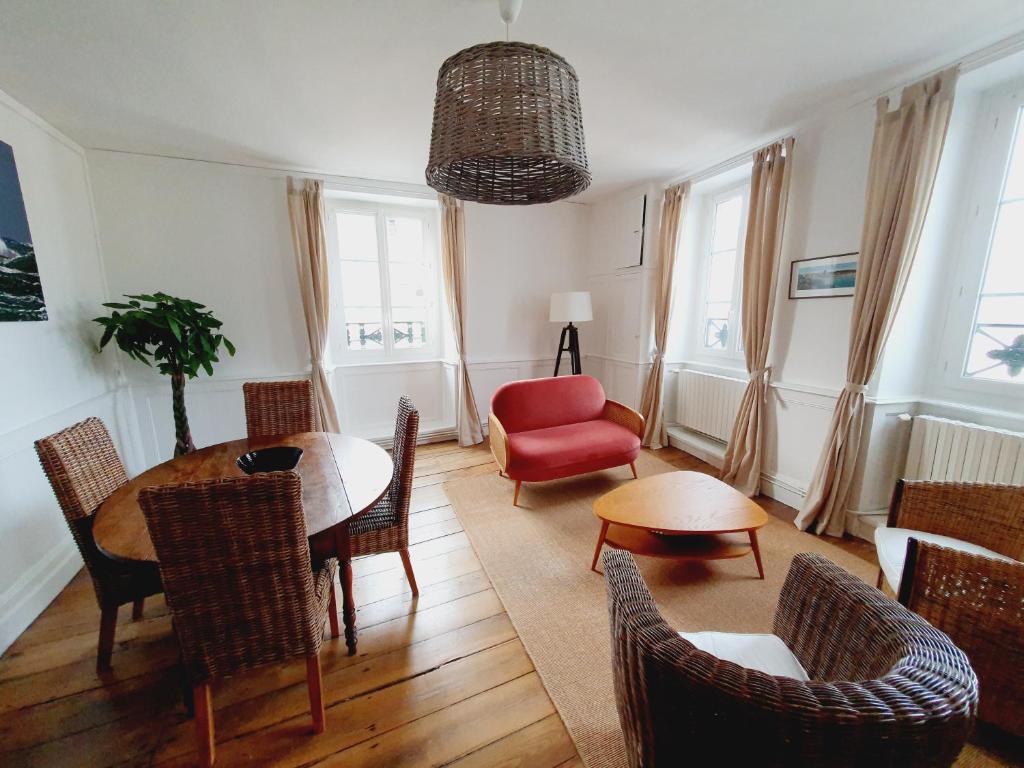 uma sala de estar com uma mesa e cadeiras e uma cadeira vermelha em Les Sablons - Très Bel Appartement , Lumineux em Saint Malo