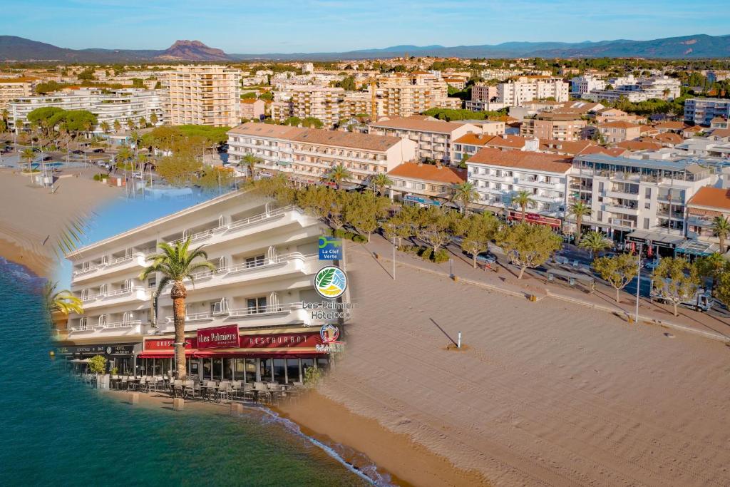 - une vue aérienne sur une plage avec des bâtiments et l'océan dans l'établissement Les Palmiers, à Fréjus