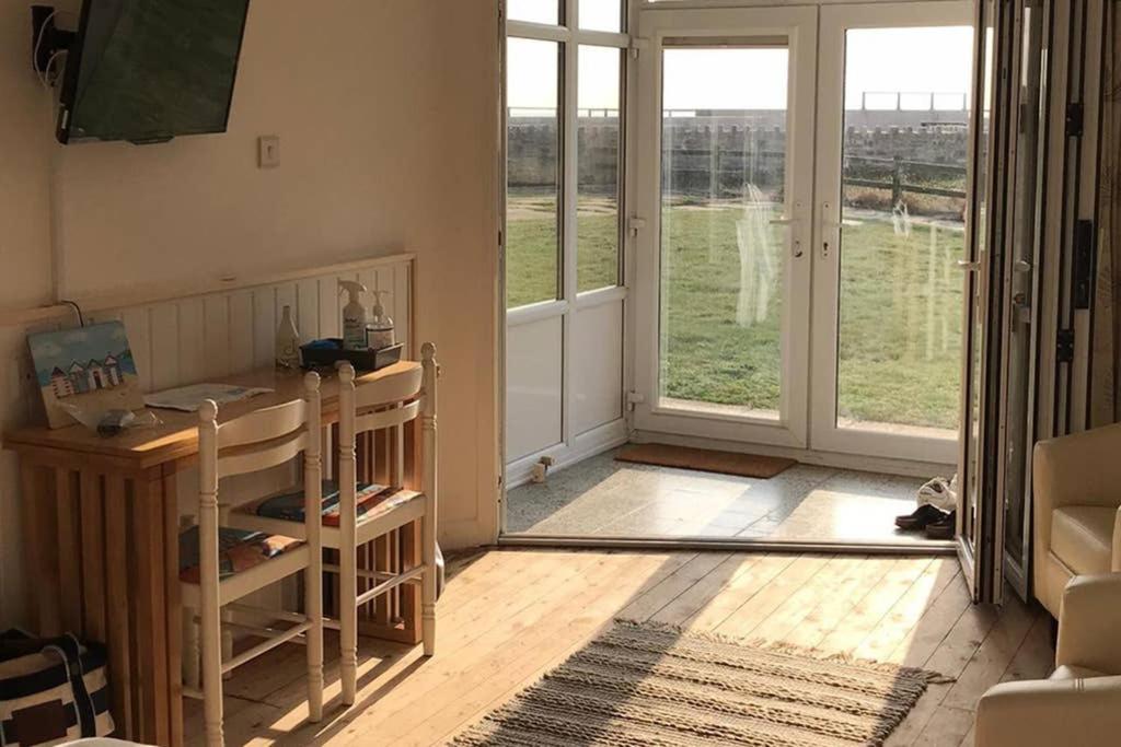 a living room with a door open to a view of a field at Seaside Studio right on the coastal path. in West Bay