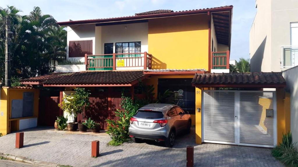 a car parked in front of a yellow house at Casa Canto Juqueí in Juquei