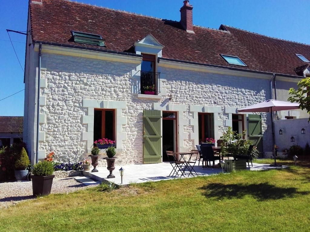 une maison en pierre blanche avec une table et des chaises dans l'établissement Les Trois Provinces, à Couffy