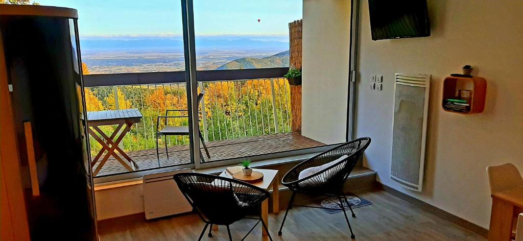 トロワ・エピにあるStudio avec sauna au calme à 15 min de Colmarのテーブルと椅子、大きな窓が備わる客室です。