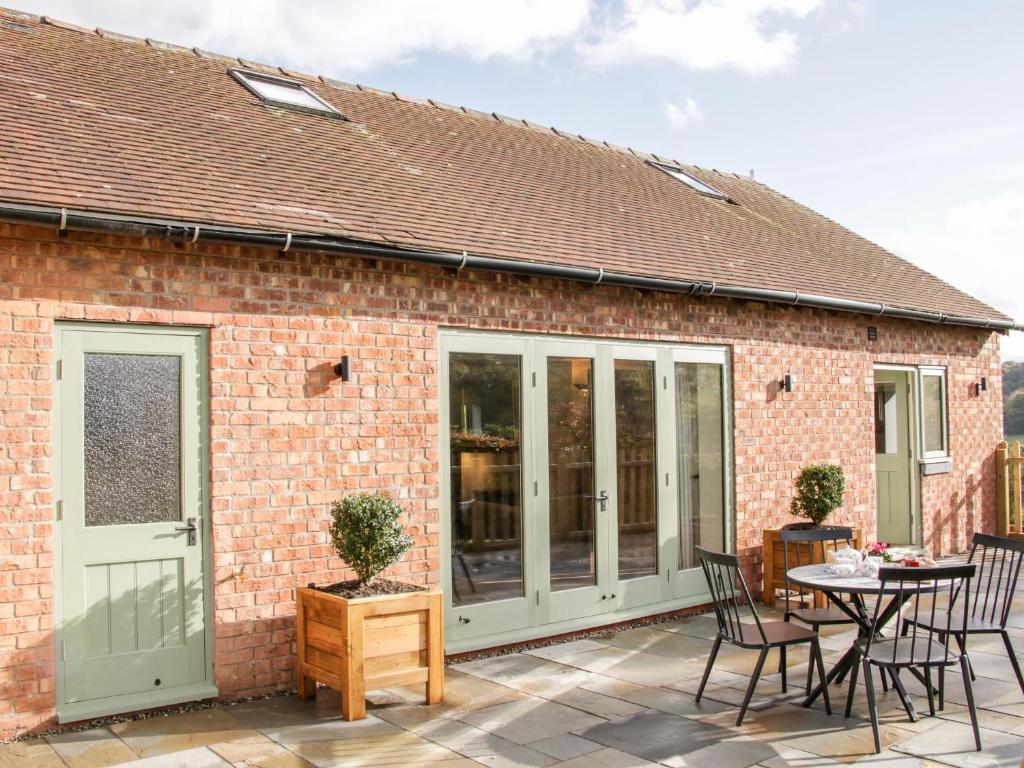 a brick house with a patio with a table and chairs at Conkers' Cottage in Church Stretton